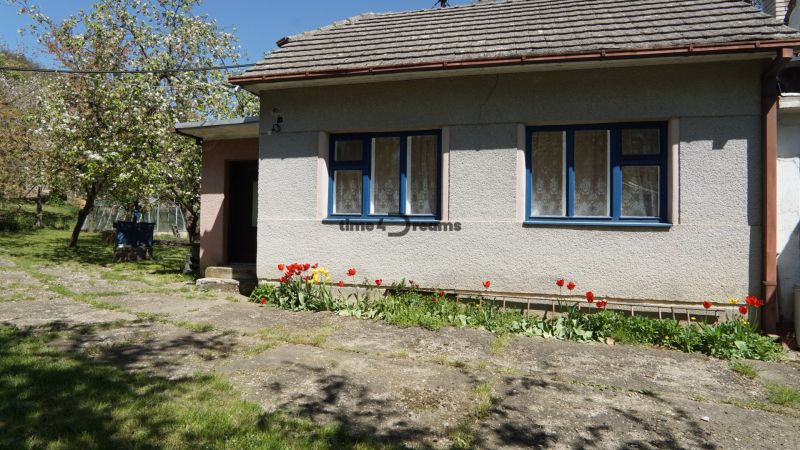 NA PREDAJ – chalupa alebo rodinný dom na pokojné bývanie  - Rodinný dom v Krajnom s kvetinami pred oknami a jarnou záhradou.