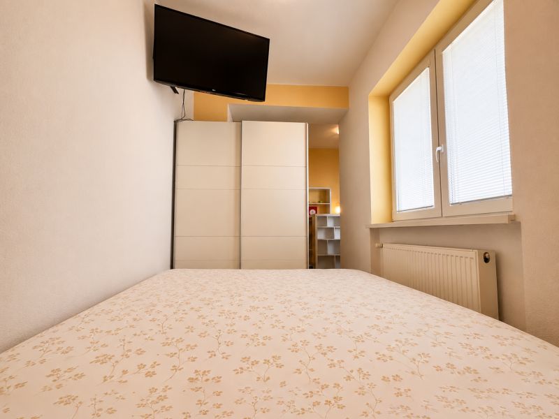 Na prenájom 1 izbový byt po rekonštrukcii – Banská Bystrica/centrum - Spálňa v 1-izbovom byte s televízorom, skriňou a oknom s roletami.