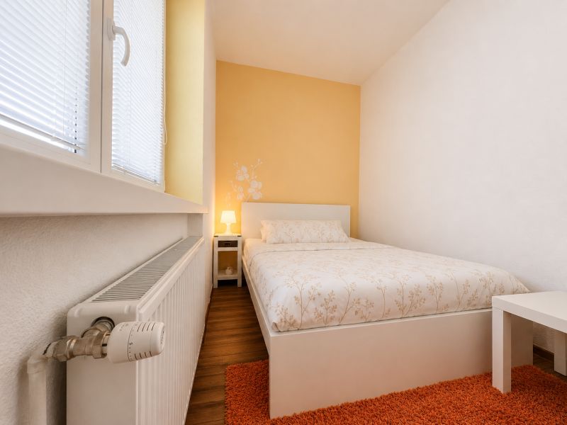 Na prenájom 1 izbový byt po rekonštrukcii – Banská Bystrica/centrum - Spálňa v 1-izbovom byte s podlahou s dreveným dekorom a oranžovým kobercom.