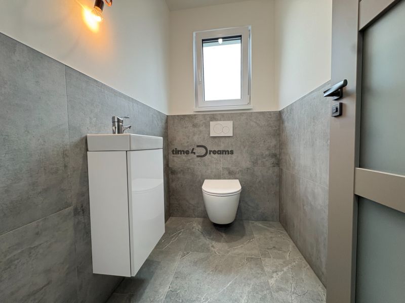 Na predaj: Novostavba rodinného domu v Leviciach - Kúpeľňa v rodinnom dome s modernou sanitou a šedými obkladmi.