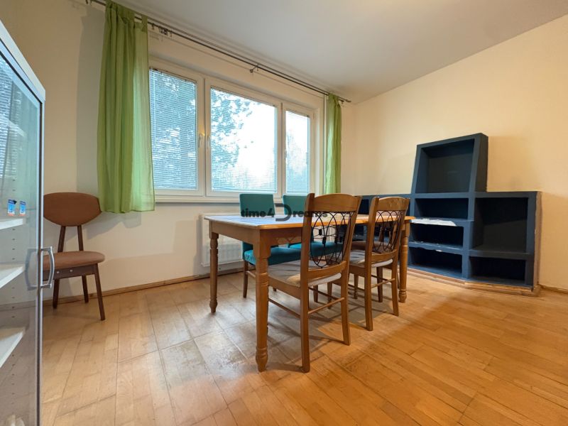 Na predaj: CENTRUM: 3 izb.byt + PIVNICA - Izba 3-izbového bytu s podlahou s dreveným dekorom, stolom a stoličkami.