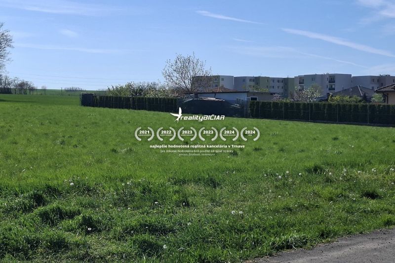 Stavebný pozemok 1212m² v obci Šelpice - Pozemok na bývanie na Slnečnej ulici v Šelpiciach s budovami v pozadí.