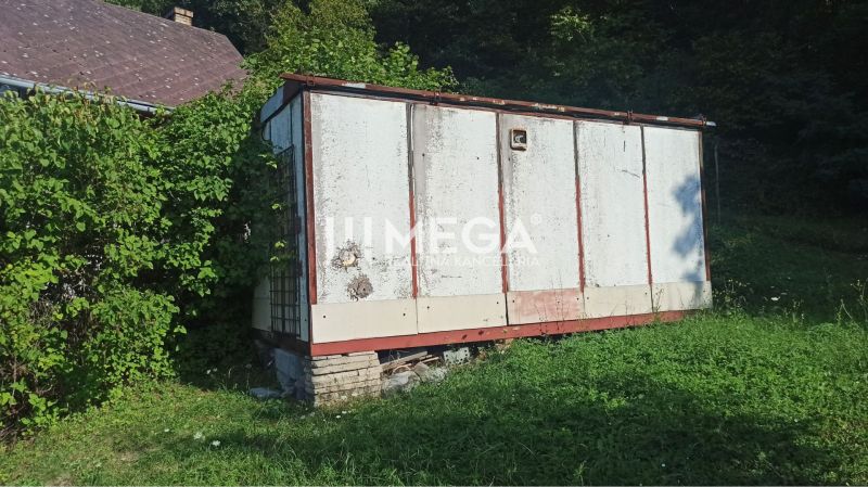 Na predaj pozemok/záhradka v záhradkárskej osade Poniklec Humenné - Starší sklad v záhrade ulice v Humennom, obklopený zeleňou a rastúcou trávou.