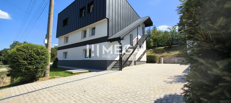 NOVINKA, na predaj tri prémiové 4 izbové byty v obci JASENOV (HE) - Štvorposchodová budova v Jasenove s vonkajšími schodmi, obklopená zeleňou a dláždeným chodníkom.