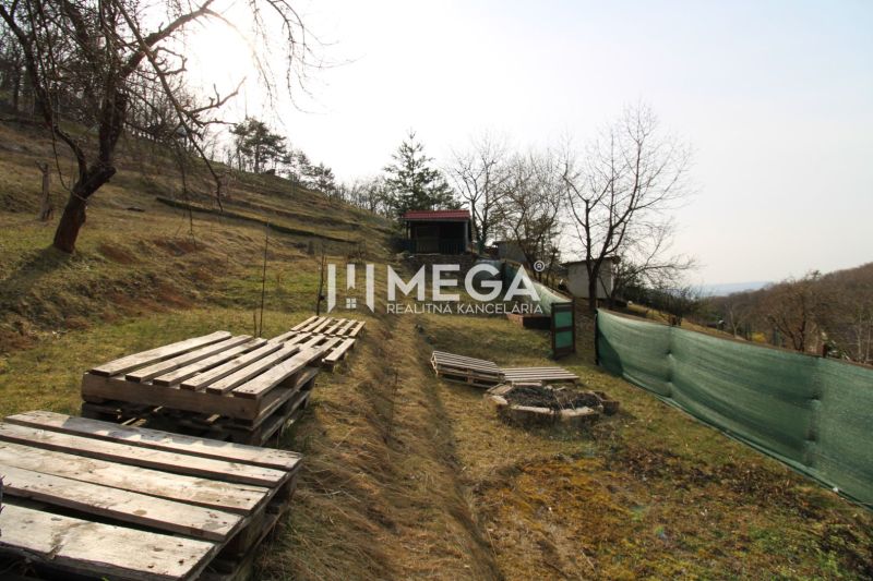 NA PREDAJ pozemok 800m2 v ZO Poniklec pri meste Humenné - Záhrady v Humennom na ZO Poniklec, trávnatý svah s paletami a dreveným altánkom.