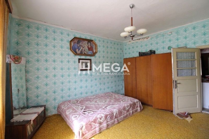 REZERVOVANÉ - Dom s krásnym pozemkom v Zbudskej Belej - Izba v rodinnom dome s posteľou, šatníkom a obrazmi na vzorovej tapete.