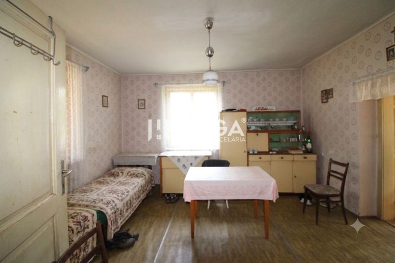 REZERVOVANÉ - Dom s krásnym pozemkom v Zbudskej Belej - Izba v rodinnom dome s tapetami, stolom, posteľou, vitrínou a podlahou s dreveným dekorom.