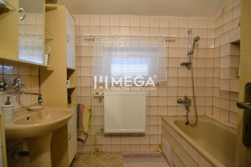 PREDAJ RODINNÉHO DOMU v obci LACKOVCE (HE) - Kúpeľňa v rodinnom dome s béžovým obkladom, vaňou a umývadlom.