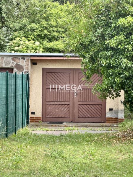 Na predaj garáž s pozemkom na sidl. IIA v meste Humenné - Garáže na ulici Osloboditeľov v Humennom s drevenou bránou, obklopené zeleňou.