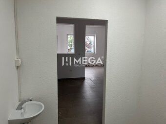 Prenájom komerčných priestorov – Snina (budova ECO umyvárky) - Interiér obchodných priestorov s umývadlom a dverami, podlaha s dreveným dekorom.