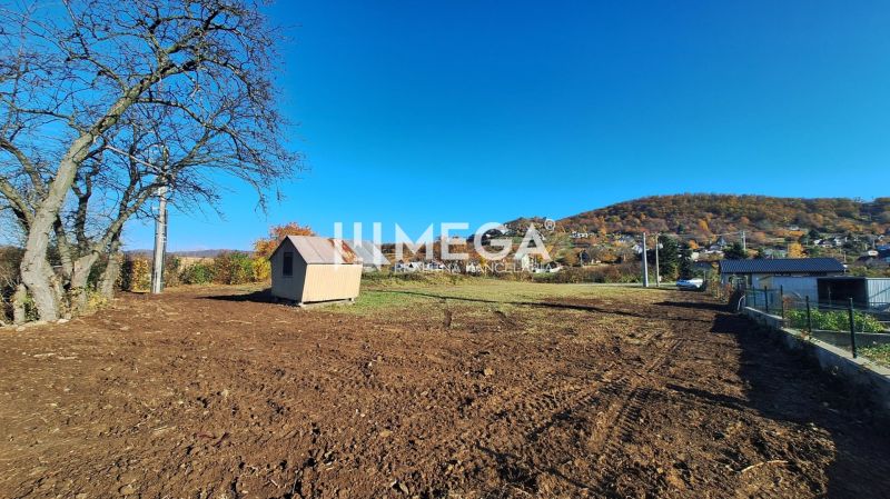 EXKLUZÍVNE NA PREDAJ 1303,5 m2 POZEMOK NA ZEMPLÍNSKEJ ŠÍRAVE - Pozemok pre bývanie v obci Vinné, s výhľadom na okolité kopce a drevený domček.