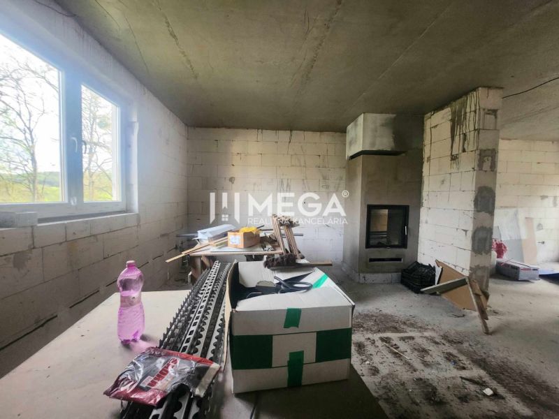 Na predaj uzavretá hrubá stavba RD, Svinica, Košice - okolie - Interiér rodinného domu s nedokončenými stenami, krbom a staveniskovým materiálom.