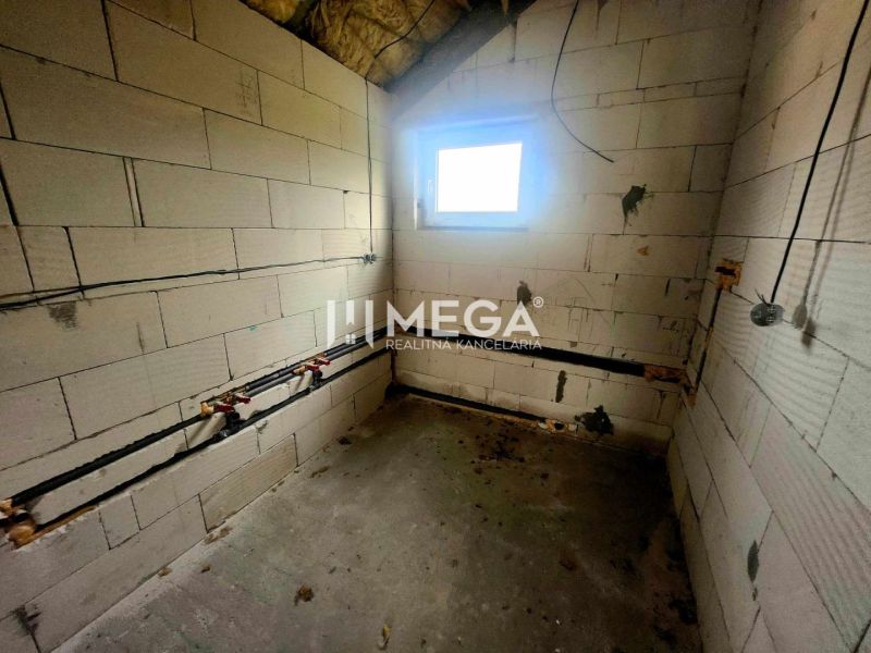 Na predaj uzavretá hrubá stavba RD, Svinica, Košice - okolie - Interiér rodinného domu s betónovou podlahou, tehlovými stenami a malým oknom.