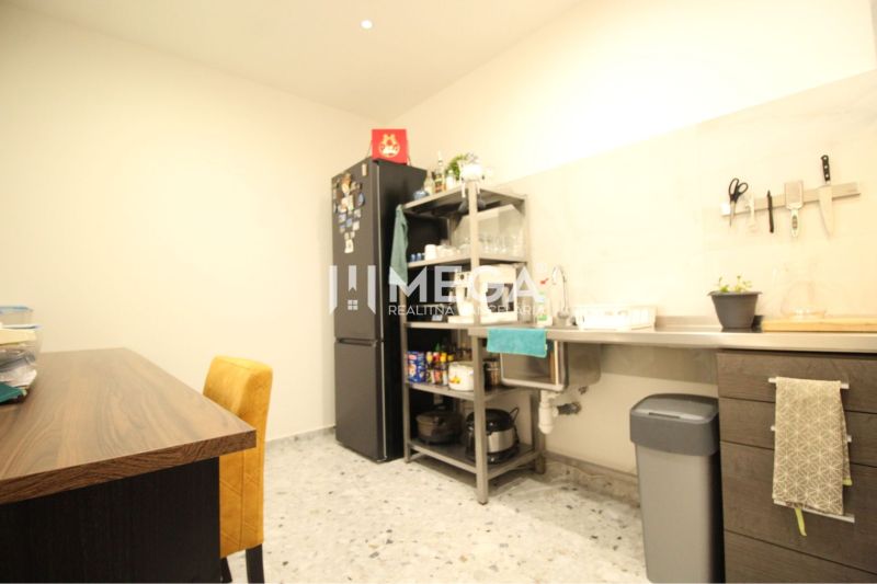 NA PRENÁJOM: Kancelárske priestory + 3-izbový apartmán – Košice - Kuchyňa v budove s pracovnou linkou, chladničkou a stolom s čalúnenou stoličkou.