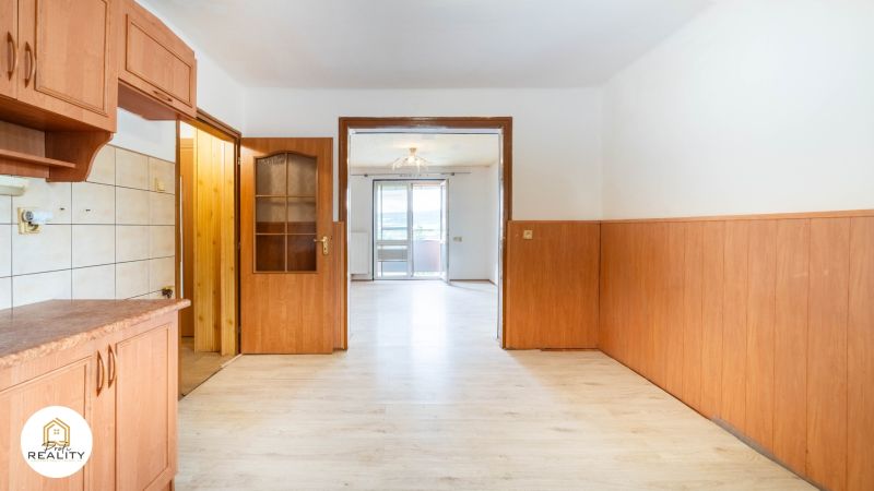 PREDAJ | 2-izb. byt 59 m² + loggia | Š. Michaľany - Interiér 2-izbového bytu s podlahou s dreveným dekorom a vstupom na balkón.