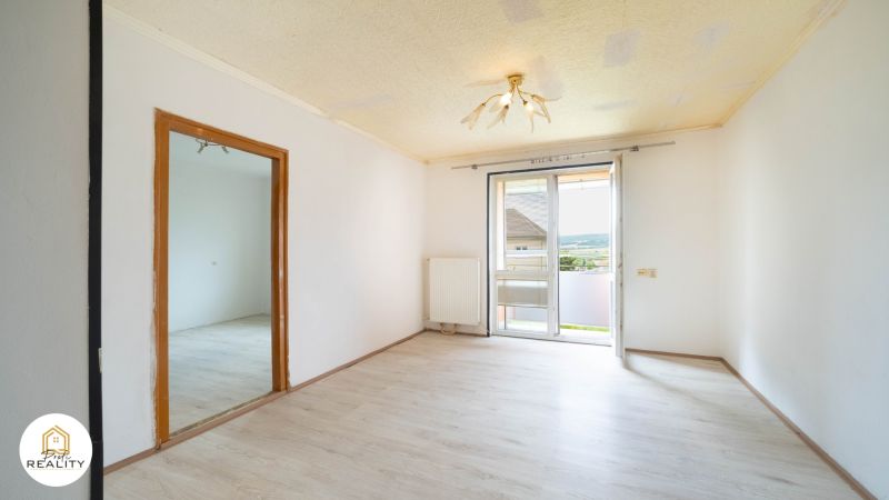 PREDAJ | 2-izb. byt 59 m² + loggia | Š. Michaľany - Interiér 2-izbového bytu s podlahou s dreveným dekorom a priamym výhľadom na balkón.