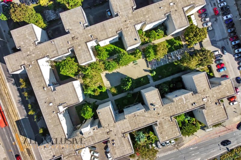 2 - IZBOVÝ BYT | BRATISLAVA III | VAJNORSKÁ  - Letecký pohľad na bytový dom obklopený stromami a parkovacím miestom v Bratislave.