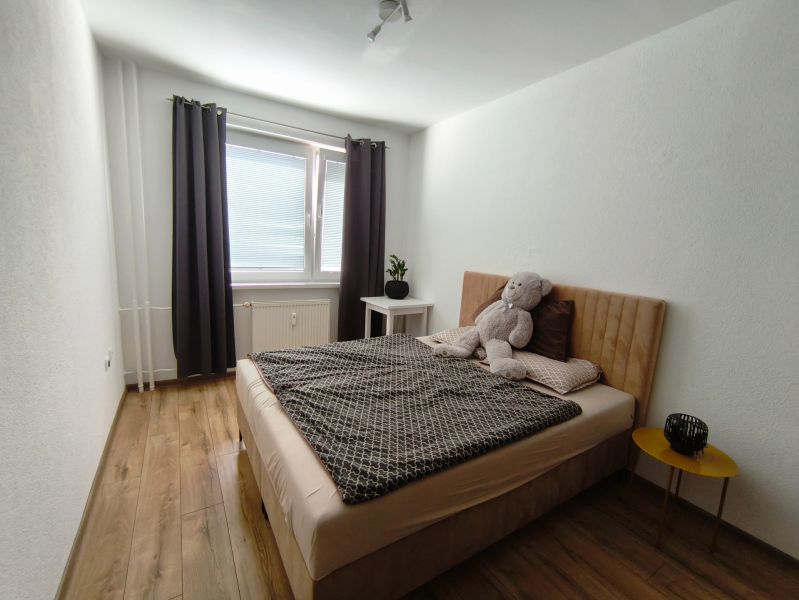 3 izbový kompletne prerobený a zariadený byt na prenájom, Necpaly  - Spálňa v 3-izbovom byte s posteľou, plyšovým medveďom a podlahou s dreveným dekorom.
