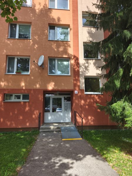 3 izbový kompletne prerobený a zariadený byt na prenájom, Necpaly  - Vchod do bytového domu na Dúbravskej ulici v Prievidzi so stromom a rampou.