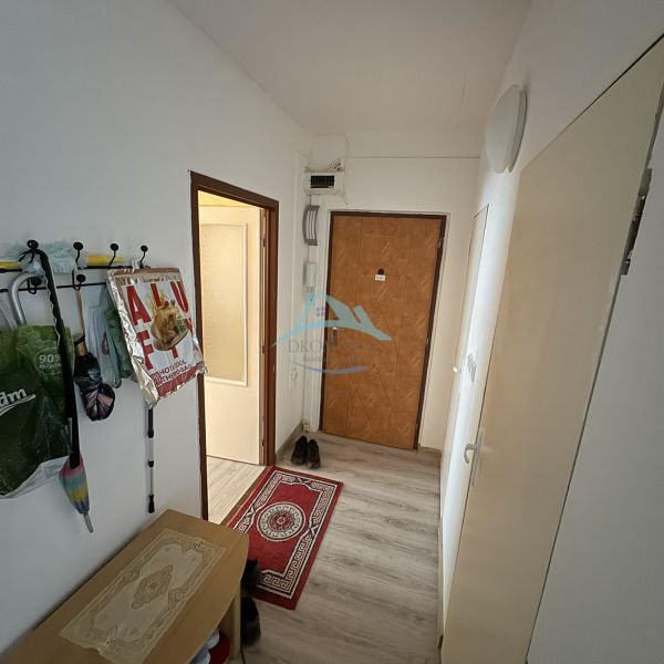Váš nový štart alebo bezpečná investícia v srdci Šiah - Chodba v 2-izbovom byte s podlahou s dreveným dekorom, vešiakom a botníkom.