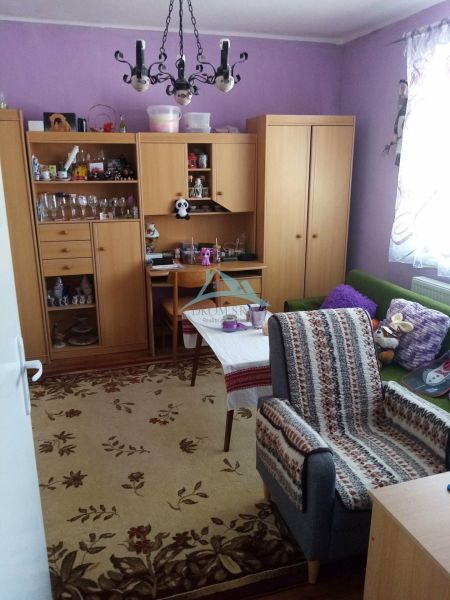 Váš nový rodinný prístav v obci Iža: Priestor, kľud a čerstvá úroda z  - Obývacia izba v Rodinnom dome s fialovými stenami a dreveným nábytkom.