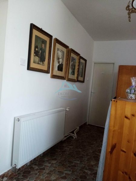 Váš nový rodinný prístav v obci Iža: Priestor, kľud a čerstvá úroda z  - Chodba v rodinnom dome s fotografiami a radiátorom, podlaha s dlažbou.