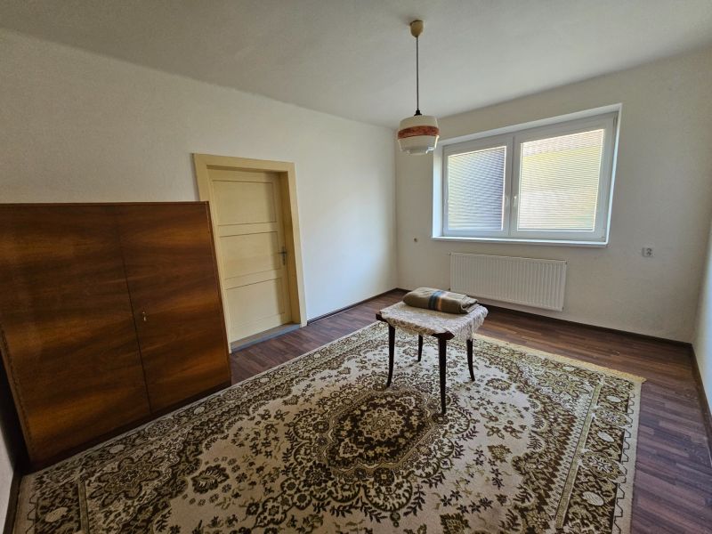 Na predaj rodinný dom s veľkou záhradou v centre V.Šariša - Miestnosť v rodinnom dome s podlahou s dreveným dekorom, kobercom a skriňou.