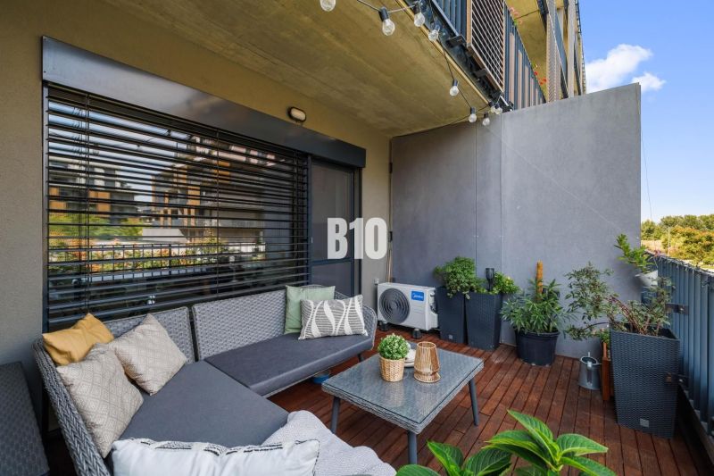 1-IZBOVÝ BYT S VEĽKOU 12 m² TERASOU | SLNEČNICE VILADOMY - Balkón 1-izbového bytu na Fialovej ulici v Bratislave V s posedením a rastlinami.