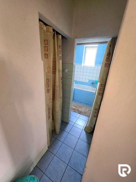 3-IZBOVÝ BYT 90 m² V RODINNOM DOME | POVAŽSKÝ CHLMEC - Žilina - Kúpeľňa v rodinnom dome s modrou vaňou a závesmi, dlažba na podlahe.