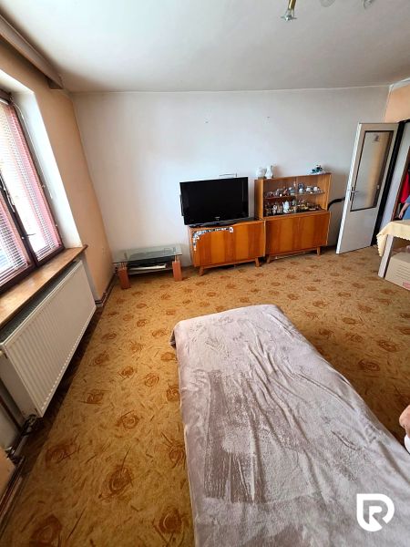 3-IZBOVÝ BYT 90 m² V RODINNOM DOME | POVAŽSKÝ CHLMEC - Žilina - Obývacia izba v rodinnom dome s televízorom, vitrínami a dekoratívnym kobercom.