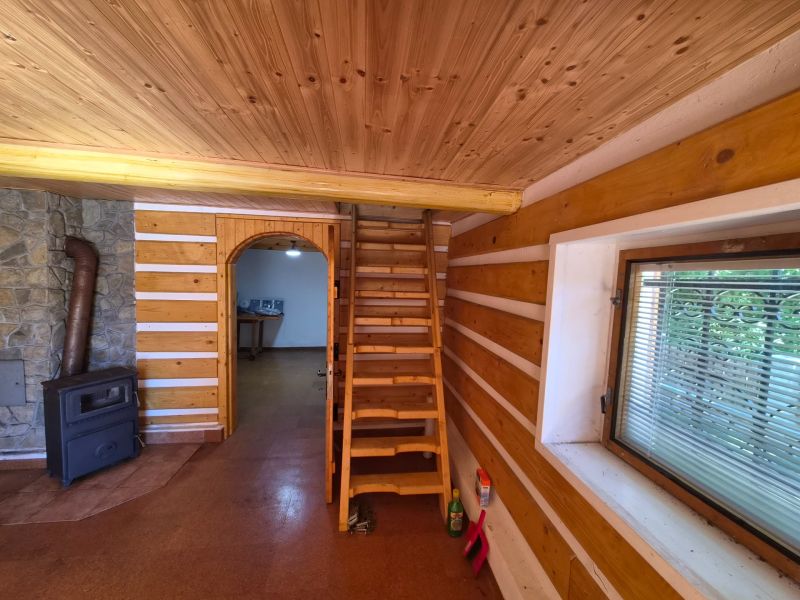 Víkendová chalupa Mikušovce, pozemok 281m2 - Drevené schodisko, sporák a kamenný obklad v rodinnom dome s podlahou s dreveným dekorom.