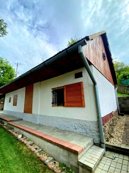 Víkendová chalupa Mikušovce, pozemok 281m2 - Rodinný dom v Mikušovciach so strešnou krytinou, drevenými okenicami a udržiavanou záhradou.