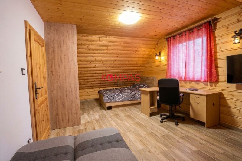 NOVOSTAVBA DOMU V MODERNOM VIDIECKOM ŠTÝLE, OBKLOPENÁ PRÍRODOU A S VEĽ - Izba v rodinnom dome s drevenými stenami, podlahou s dreveným dekorom a pracovným stolom.