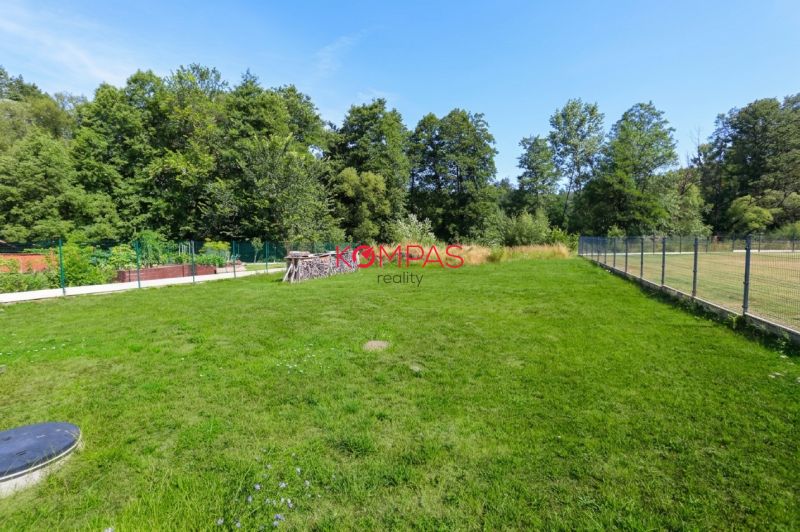 NOVOSTAVBA DOMU V MODERNOM VIDIECKOM ŠTÝLE, OBKLOPENÁ PRÍRODOU A S VEĽ - Záhrada rodinného domu v Očovej s trávnikom a oplotením, obklopená lesom.