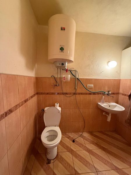 DOM NA PREDAJ, Obec Sikenica, okres Levice - Kúpeľňa s toaletou, ohrievač vody, umývadlo, podlaha s dreveným dekorom v rodinnom dome.