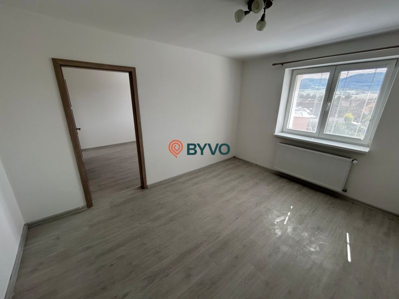 3-IZBOVÝ TEHLOVÝ BYT V DUBNICI N/V, BALKÓN, VLASTNÉ KÚRENIE A VÝBORNÉ  - Izba s podlahou s dreveným dekorom, bielymi stenami a veľkým oknom v 3-izbovom byte.