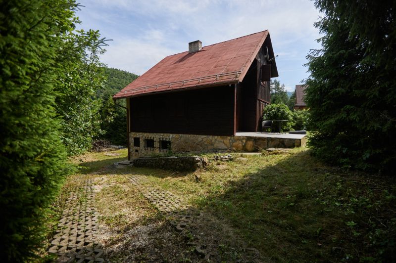NA PREDAJ-CELOROČNE OBÝVATEĽNÁ CHATA S KRBOM PRI RUŽÍNE - Chata na ulici Rovné 61 v Jaklovciach, obklopená zeleňou a stromami.