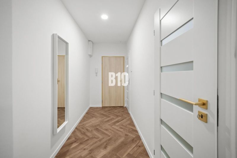 Prémiové bývanie v centre Nitry | 3 izby, veľký balkón - Chodba 3-izbového bytu s podlahou s dreveným dekorom a zrkadlom na stene.