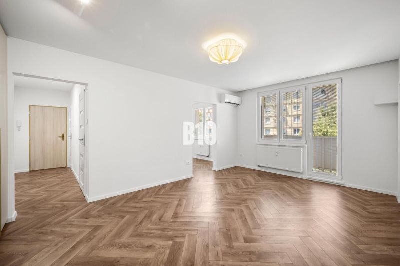 Prémiové bývanie v centre Nitry | 3 izby, veľký balkón - Obývacia izba v 3-izbovom byte so vzorovanou podlahou s dreveným dekorom.
