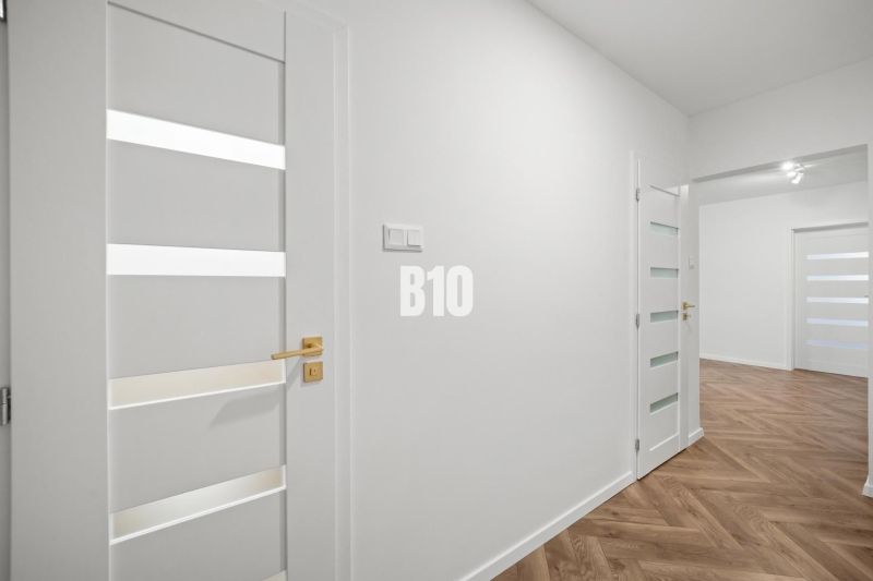 Prémiové bývanie v centre Nitry | 3 izby, veľký balkón - Biely interiér 3-izbového bytu s podlahou s dreveným dekorom a elegantnými dverami.