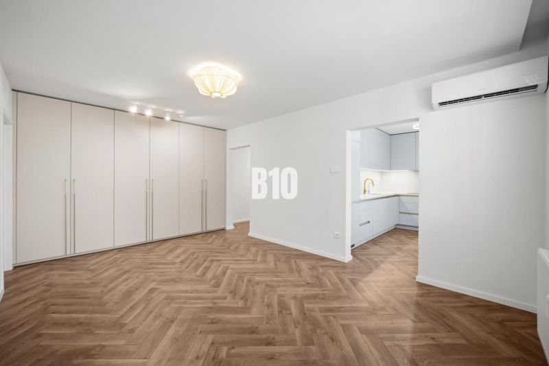 Prémiové bývanie v centre Nitry | 3 izby, veľký balkón - Obývacia izba v 3-izbovom byte s podlahou s dreveným dekorom a vstavanou skriňou.
