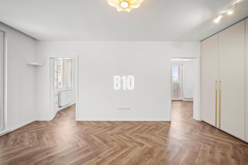 Prémiové bývanie v centre Nitry | 3 izby, veľký balkón - Izba v 3-izbovom byte s podlahou s dreveným dekorom a vstavanými skriňami.