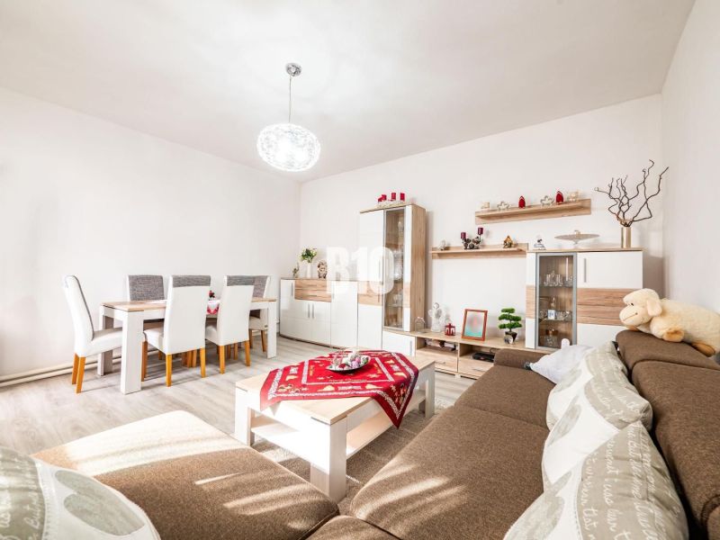 Prerobený dom, 981 m2 pozemok - Chrenová, Nitra (TOP lokalita) - Obývacia izba s jedálenským stolom, podlahou s dreveným dekorom a hnedou sedačkou v rodinnom dome.