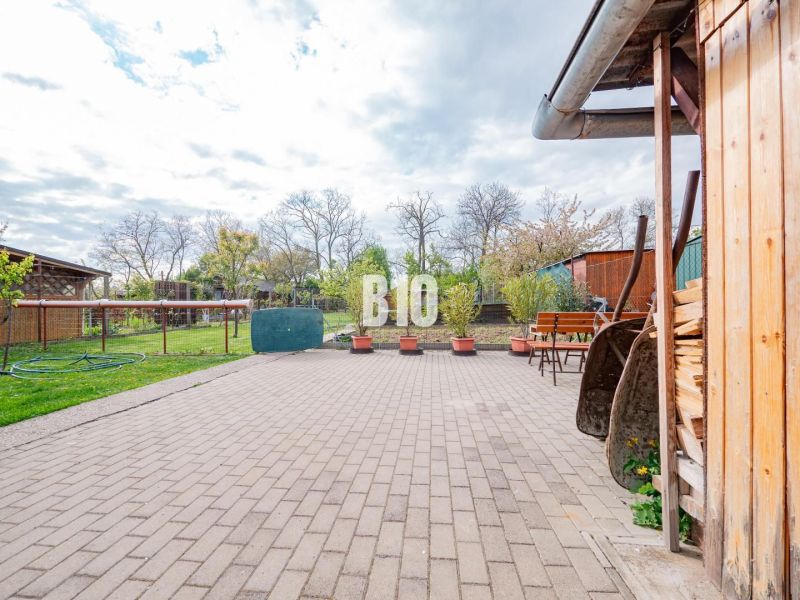 Prerobený dom, 981 m2 pozemok - Chrenová, Nitra (TOP lokalita) - Dvor rodinného domu v Nitre s vydláždenou terasou, zeleňou a drevárne.
