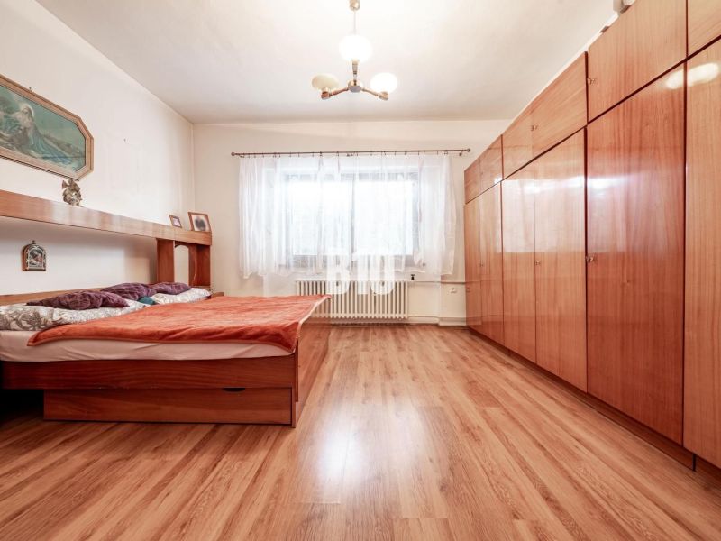 Prerobený dom, 981 m2 pozemok - Chrenová, Nitra (TOP lokalita) - Spálňa v rodinnom dome s posteľou, skriňou a podlahou s dreveným dekorom.