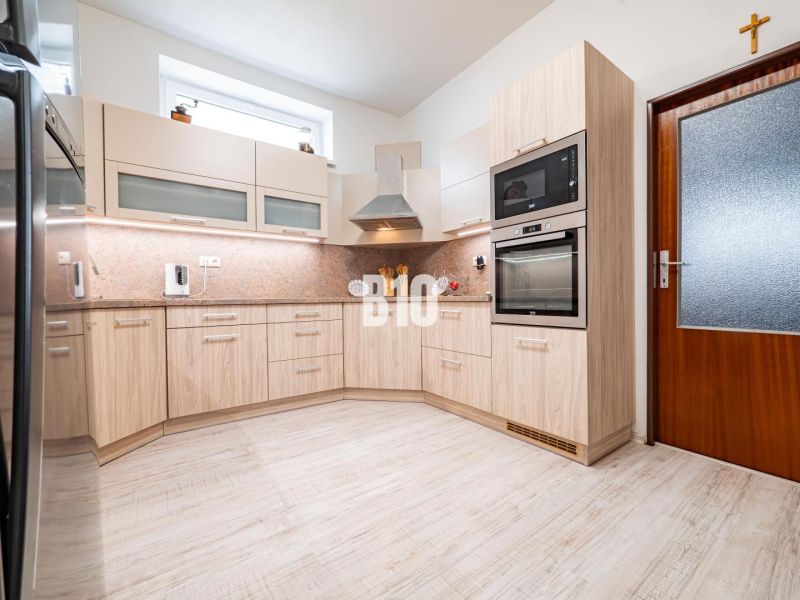 Prerobený dom, 981 m2 pozemok - Chrenová, Nitra (TOP lokalita) - Kuchyňa vo svetlých tónoch s podlahou s dreveným dekorom a vstavanými spotrebičmi.