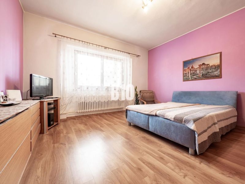 Prerobený dom, 981 m2 pozemok - Chrenová, Nitra (TOP lokalita) - Spálňa v rodinnom dome s podlahou s dreveným dekorom, nábytkom a televízorom.