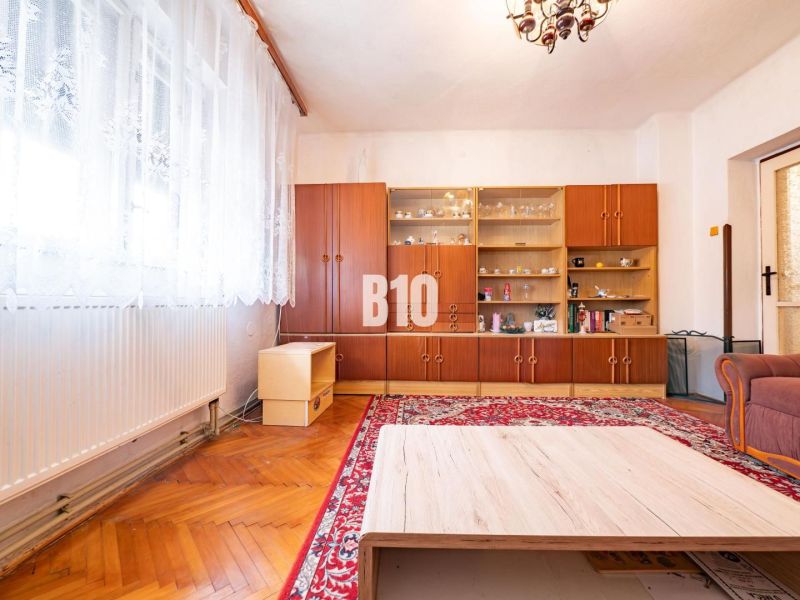 DOM, 1439 m2 pozemkom - Zbehy, Nitra (investičný potenciál) - Obývacia izba s prehľadnou vitrínou, podlahou s dreveným dekorom a červeným kobercom v rodinnom dome.
