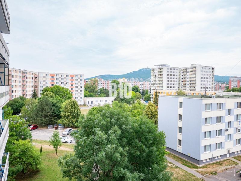 Nový 3 izb. byt s 2x balkónom, Nitra - Chrenová (2026) - Výhľad z 3-izbového bytu v Nitre na panelové domy a parkovisko s automobilmi.