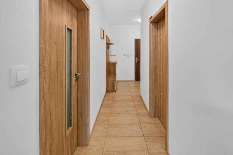 Predaj 2-izbový byt GREEN VILLAGE, loggia, parkovanie, Dunajská Lužná - Chodba v 2-izbovom byte s dreveným nábytkom a podlahou s dreveným dekorom.